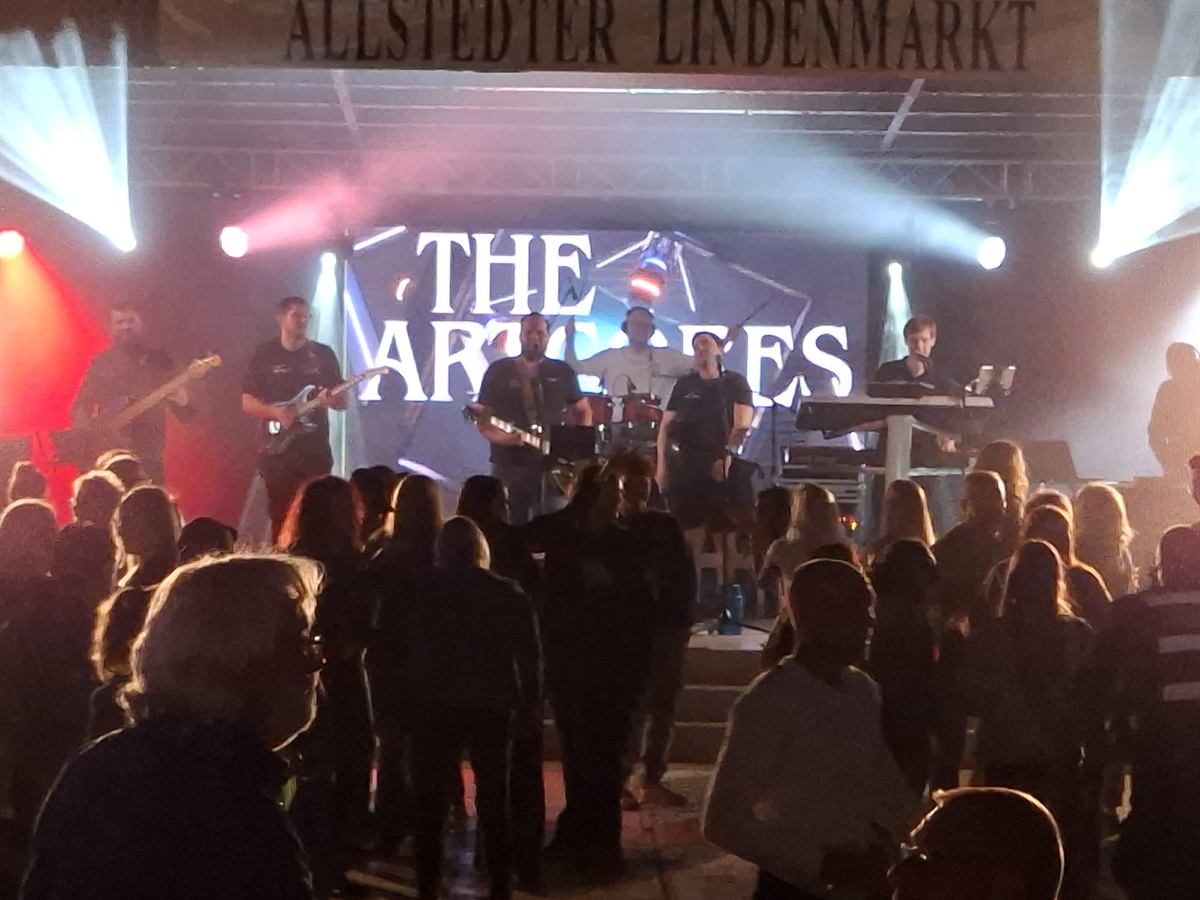 Band auf der Bühne vor einer LED-Wand mit dem Schriftzug The Artcores, davor Publikum