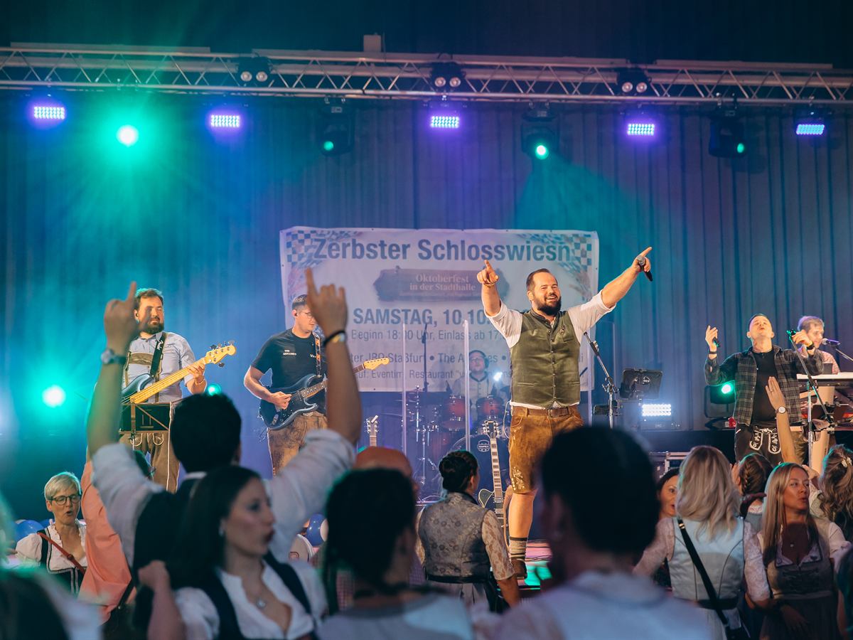 Band auf der Bühne, davor Publikum mit erhobenen Armen